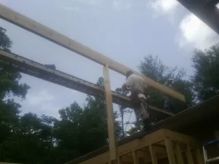 Carpenter setting a ridge beam over a new addition frame — Ice Dam Removal by Roofing Brothers in Marine