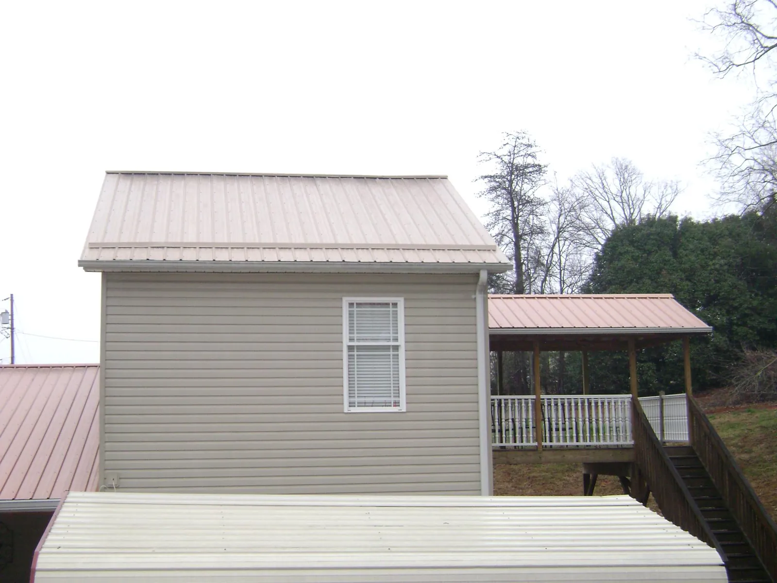 Tan metal roofs on a two story addition and attached porch, from a Roof Replacement job in Marine