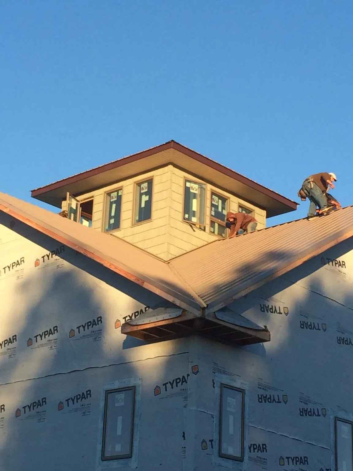 Roofers working around a rooftop cupola on a new metal roof at sunset — Roof Waterproofing in Marine by Roofing Brothers
